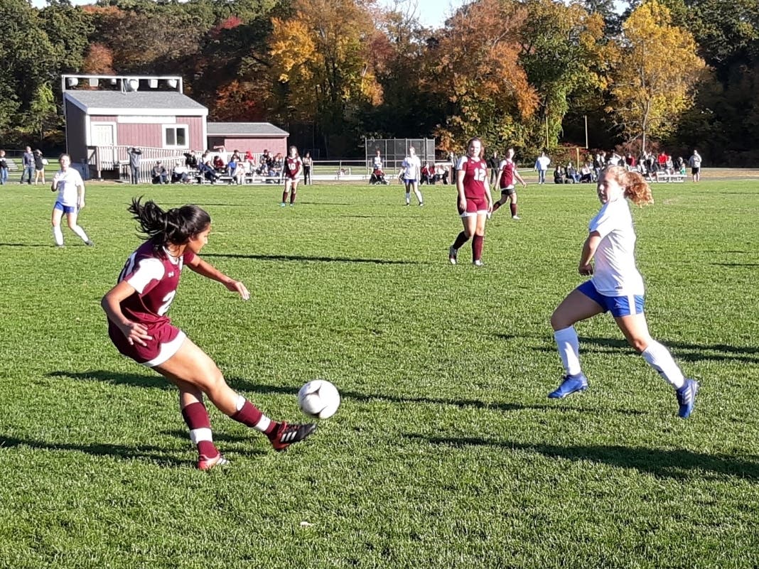 Saanya Sharma of Windsor Locks boots the ball past Suffield's Kati Davis during first-half action Monday.