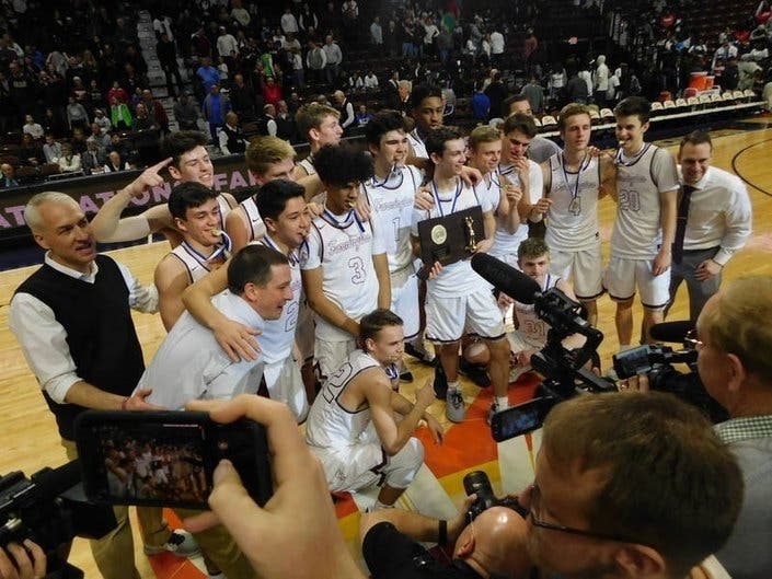 Farmington boys basketball players and coaches celebrate their victory in the 2019 Div. III championship game at Mohegan Sun Arena.