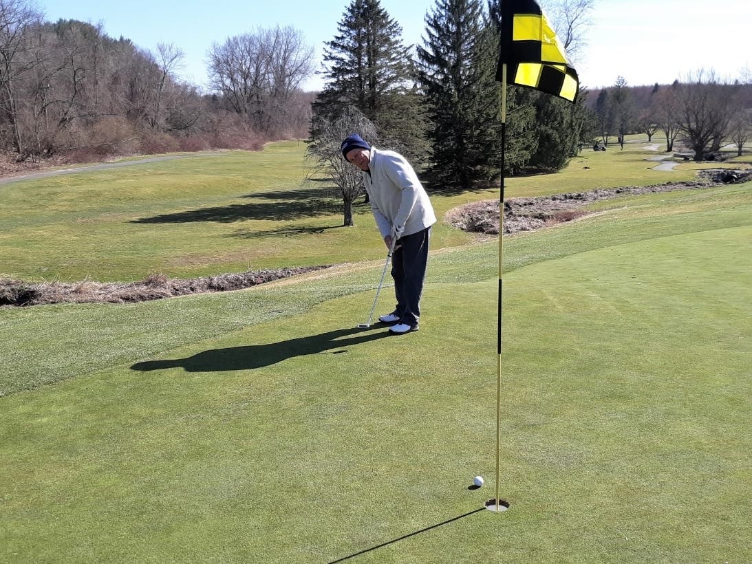 Mike DiBattisto of Enfield sinks a putt on the ninth green at Grassmere Country Club Sunday afternoon.