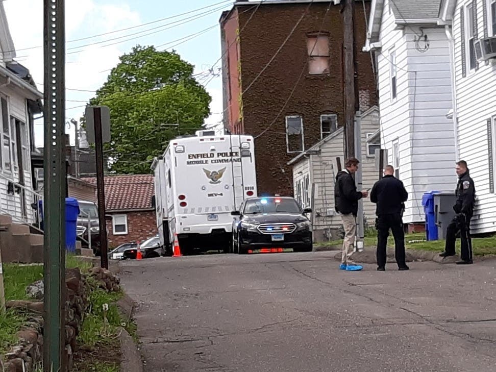 Enfield police and detectives, as well as the police department's mobile command unit, work on Wallace Street Thursday morning after a middle-aged woman's body was found in a driveway.