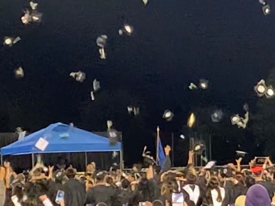 Graduates celebrate the closing of the commencement ceremony by flinging their caps into the air.