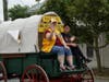 Lions Club president Angela H. and LEO Club president Lea B. cruise down Main Street in a frontier wagon. 