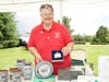 Angela M. displays Newtown Heritage Festival commemoratives at Information Tent on the Commons.