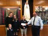 Deacon Dominic Corraro presents a check from the St. Mary School community to the Yeater family, who brought the idea of supporting Breast Cancer Awareness.