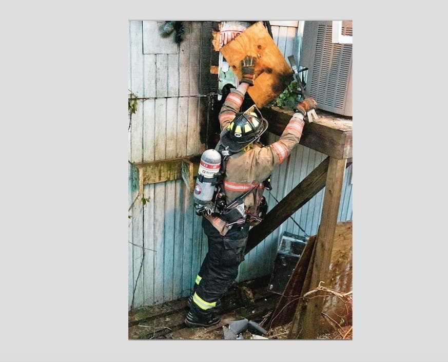 Westhampton Beach probationary firefighter Sal DiBenedetto rips away some siding during overhaul.