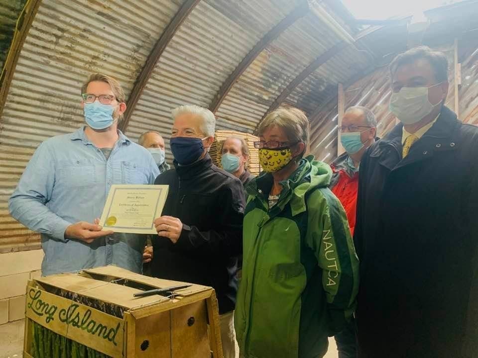 Suffolk County Executive Steve Bellone, along with Matt and Jessica Wells, Lyle's children, and Suffolk County Legislator Al Krupski, gathered as the preservation agreement was signed, fittingly, on an asparagus box.