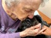 Beloved certified therapy dog, Maggie, receives a kiss from a Chestnut Knoll resident during her weekly visit. Research suggests that interactions with a therapy dog, such as cuddling, positively impact a person’s well-being.