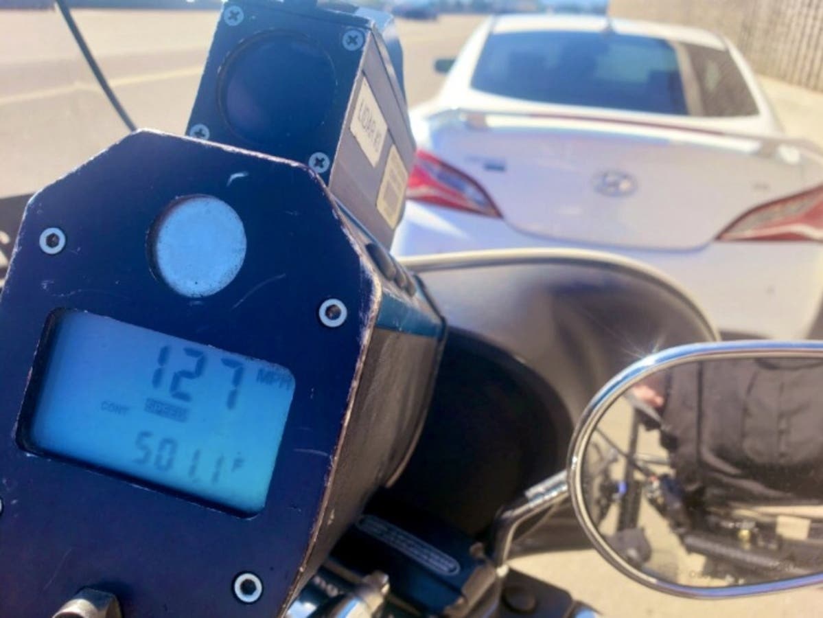 An officer issuing a ticket for 127 mph shows the speed captured on the radar.