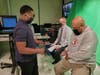 A District 228 TV Production student helps Bremen High School Athletic Director Eric Washington attach his microphone as he prepares to serve as a guest judge for "Bake Off!"
