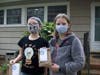 Eleven-year-old twins, Phebe, left, and Delphia Greeley hold bags of cookies to deliver to their neighbors in Admiral Heights.