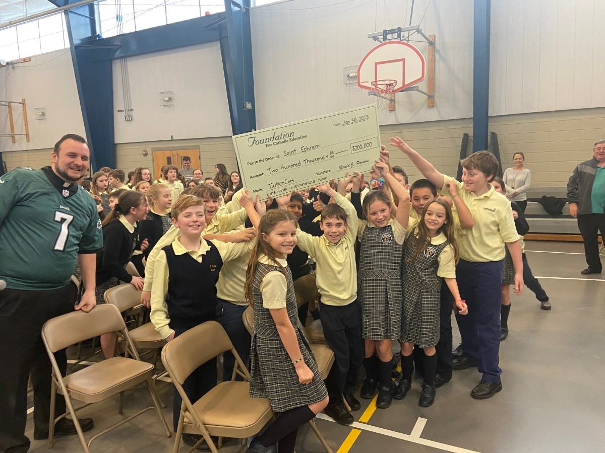 Saint Ephrem Catholic School students hold up a $200,000 check for tuition reimbursement. 