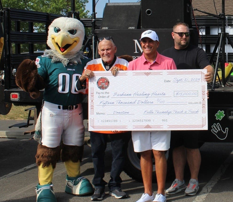 Philadelphia Eagles mascot Swoop joins Falls Supervisor Jeff Boraski (right) in presenting a $15,000 check. Former Philadelphia Flyers player Bernie Parent and The Barkann Family Healing Hearts Foundation Executive Director Mike Barnes accept the check