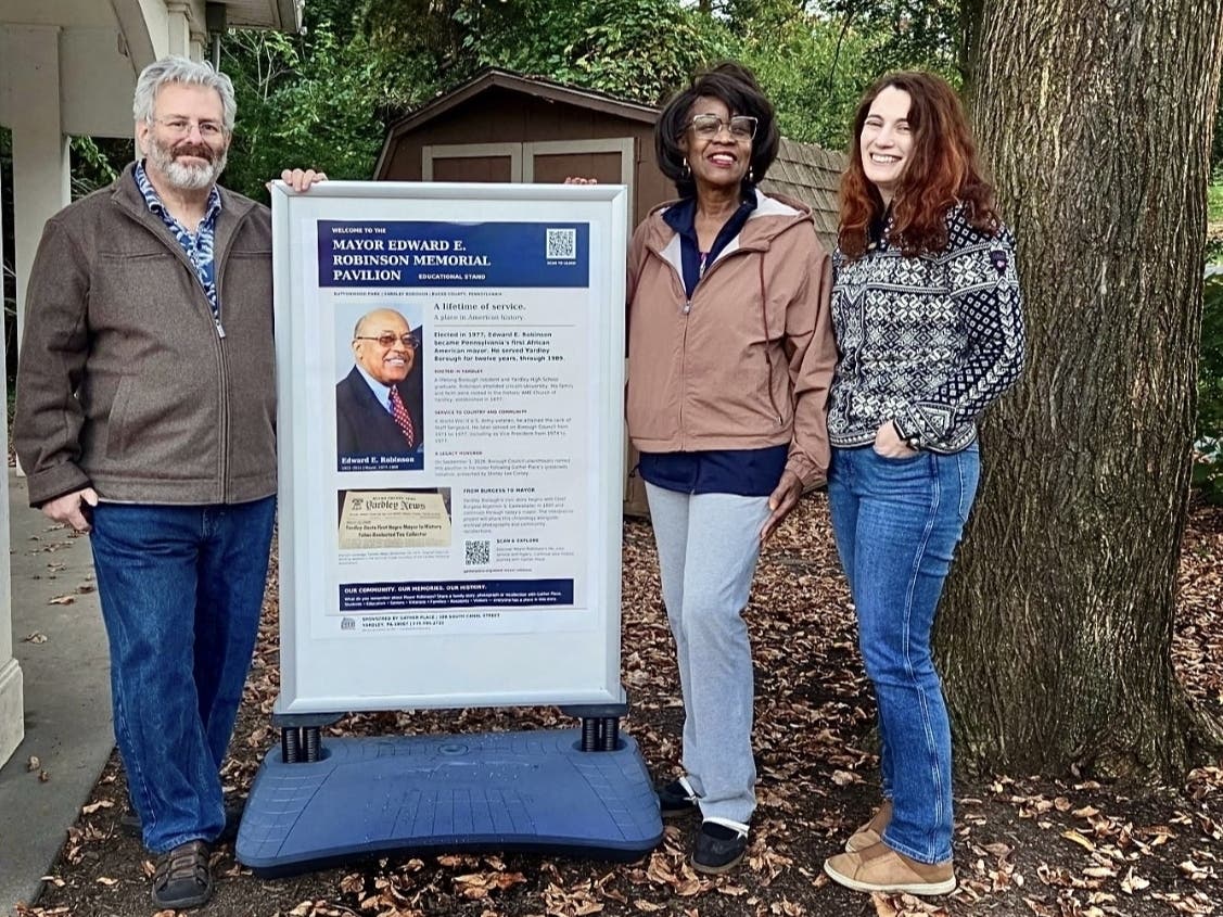 David Appelbaum, President of Yardley Borough Council; Shirley Corsey, Executive Director of The Gather Place; and Martha Howlett, Yardley Borough Councilwoman, stand beside the newly installed educational display honoring Mayor Edward Robinson.