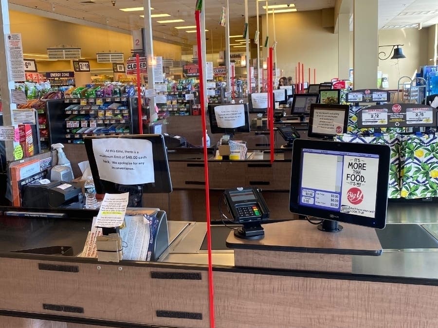 Images shows plexiglass screens at cashier stations. 