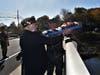Donald Langlois and Dennis Flanigan drop a wreath off the South Montowese Street bridge at the Naval ceremonies.