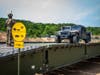A Soldier assigned to the Connecticut National Guard's 250th Multi-Role Bridge Company ground guide’s a Humvee across the unit’s Dry Support Bridge they constructed at Stones Ranch Military Reservation, June, 10, 2020. 