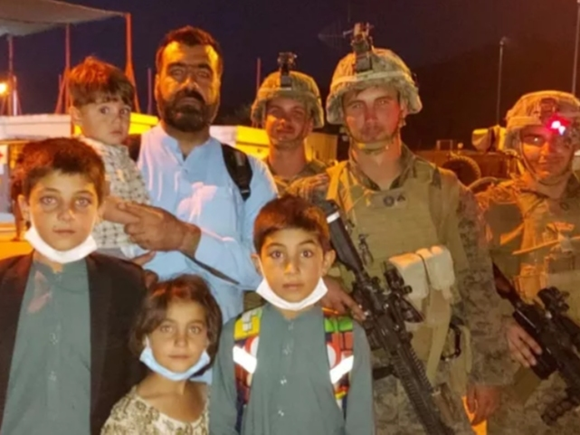 Atifullah Ahmadzai ​and his family had just made it though the gates at Kabul International Airport​ when the photo was taken of he, and four of his five children accompanied by U.S. Marines. 