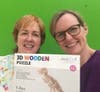 Katie Lyons and Lori Lee with the dinosaur puzzle that inspired the set design 