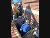The Facilities crew works together to extract the heavy cornerstone from the building's masonry.