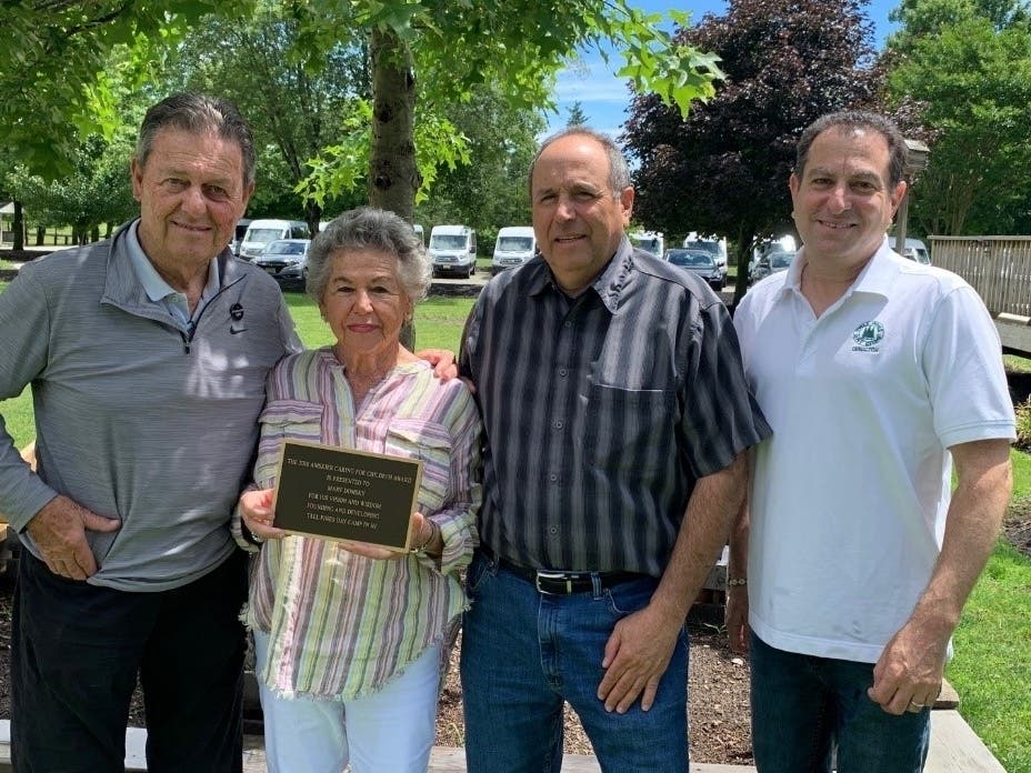 (From left to right): Henry M. Skier, President of AMSkier, who presented the Award; Carole Domsky, the wife of Marvin; Sam Domsky, a son of Marvin; and Andrew Yankowitz, Director and Owner of Tall Pines Day Camp