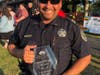 Police Lieutenant Mke Rodriguez holding the 'Best Friends' of the Park District' award.