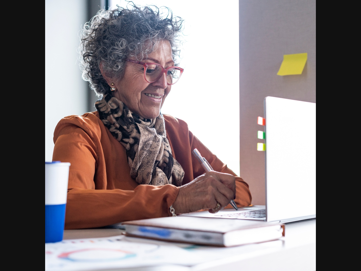 An older adult sitting at a desk with a laptop.