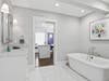 Spa-like primary bath finished in marble with dual vanities, a soaking tub, and a rain shower. The private water closet includes a bidet, and the suite offers direct access to one of two walk-in closets for seamless daily function and comfort.