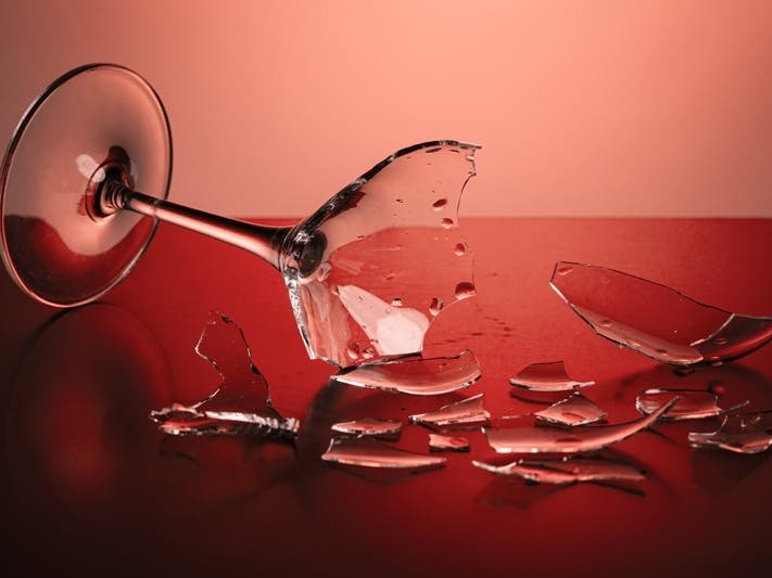 broken wineglass on the table with colored background