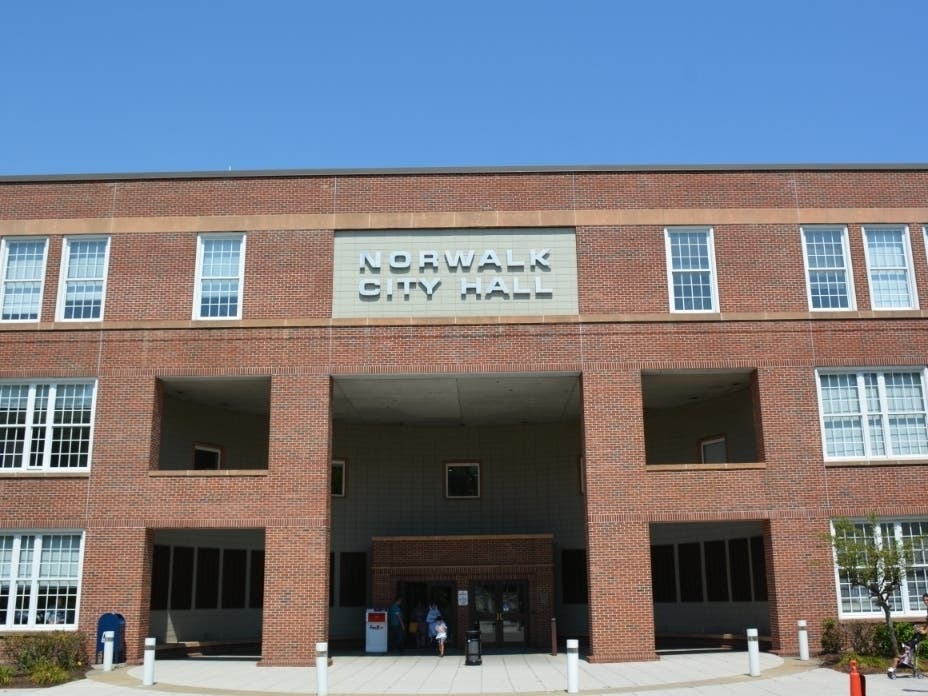 A 70-year-old seasonal Norwalk government employee was arrested on a warrant Thursday charging him with 32 counts of second-degree forgery.