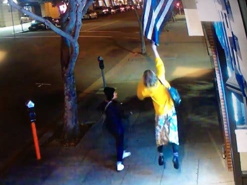 A woman snatches an American flag from in front of a business