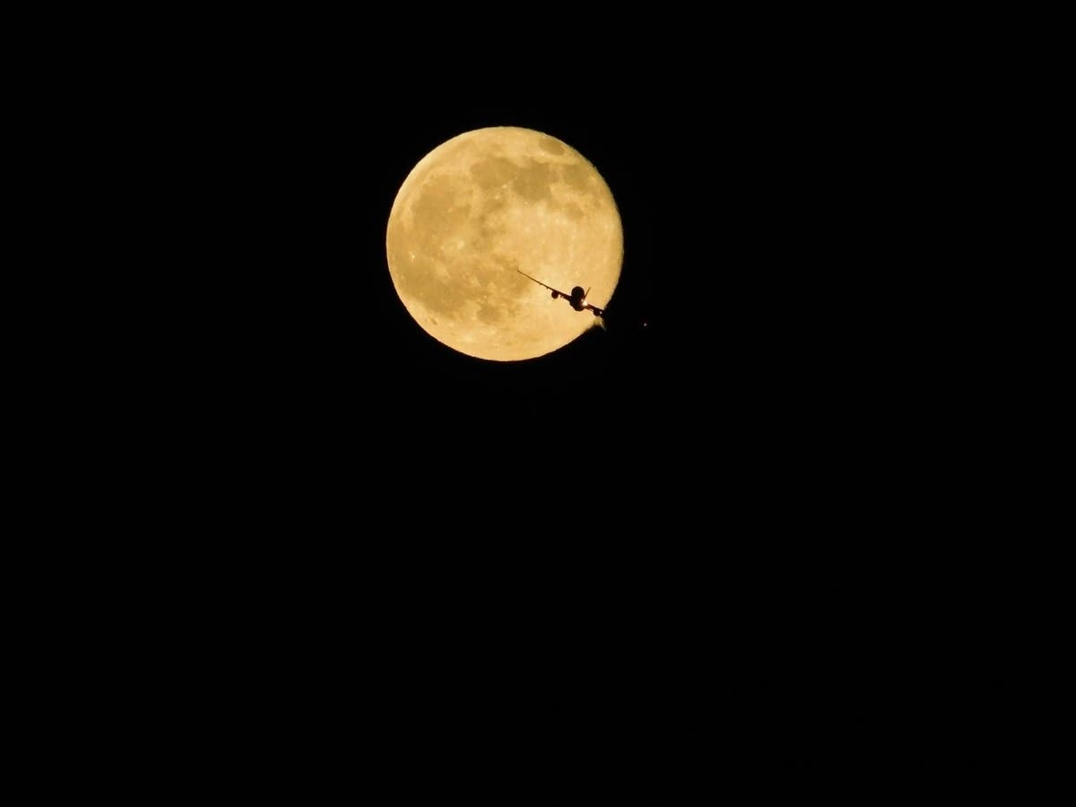 An airplane flies in front of the moon. Photo taken in San Lorenzo, Calif.