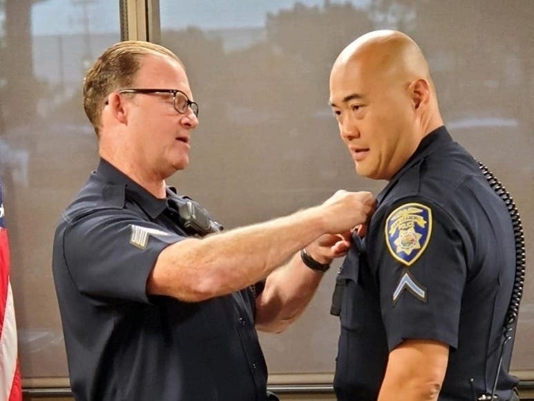 Sgt. Clifford pinning badge number one on Officer Kwan in San Leandro, Calif.