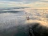 The towers of the Golden Gate Bridge poking out of the fog as it rolls into the bay.