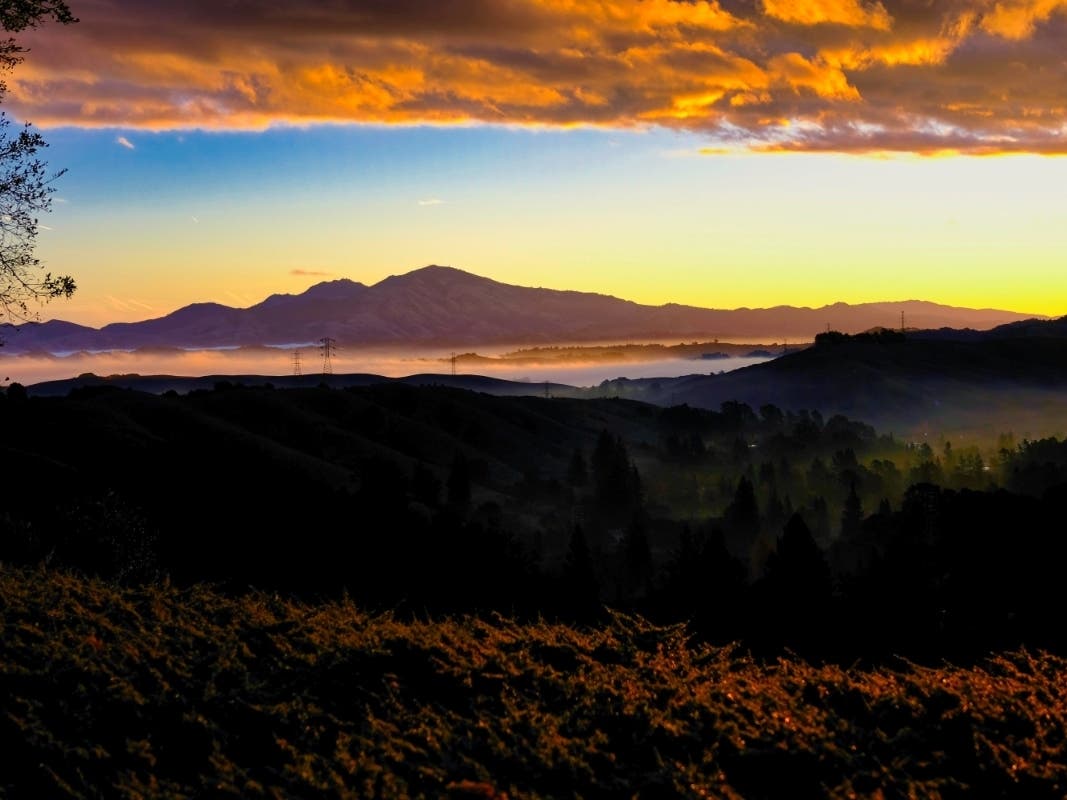 Clouds above and below frame Mt. Diablo at sunrise. Photo taken from Orinda, Calif.