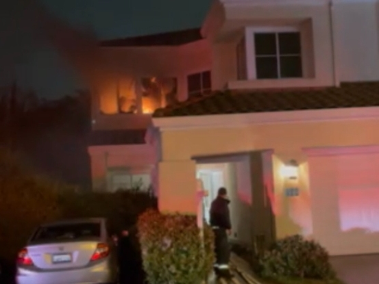 Flames are visible in the upstairs bedroom of a home on Fundy Bay in Alameda Tuesday night, as firefighters laid their hoses but before water was flowing to fight the flames.