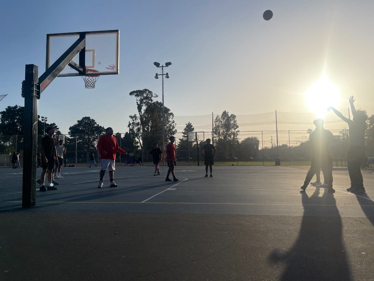 Captured in mid-flight, teammates and defenders await the conclusion of a three point attempt at Upper Washington Park.