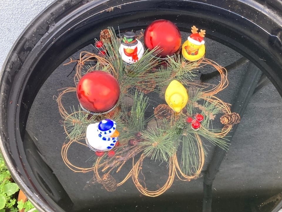Rubber duckies decked out for the holidays take a swim, along with a wreath and other holiday decorations.