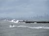 People walk on the Rock Wall as one person rides the waves on a jet ski in Alameda, Calif.