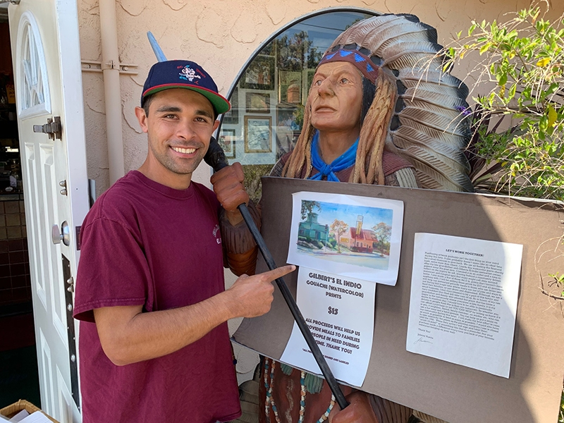 Johnny Huerta with his painting, held up by the iconic 'indio' outside the restaurant