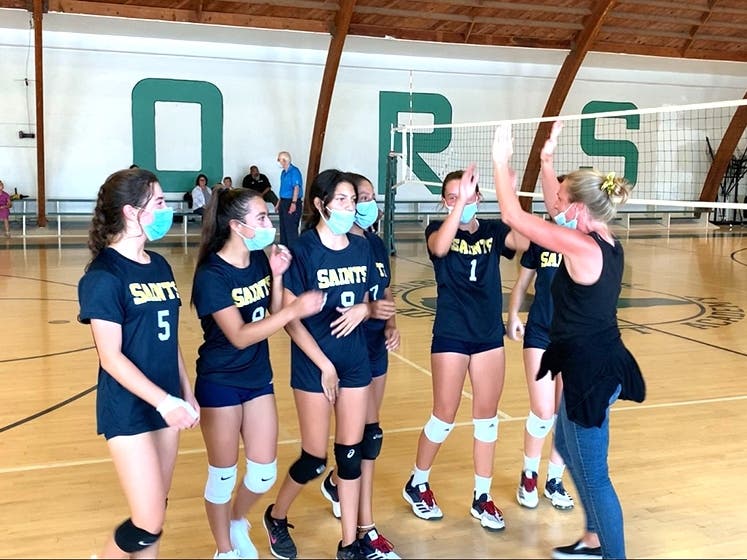 Coach Jessica Young congratulates the girls for a last-gasp win in set 3 to turn the momentum.
