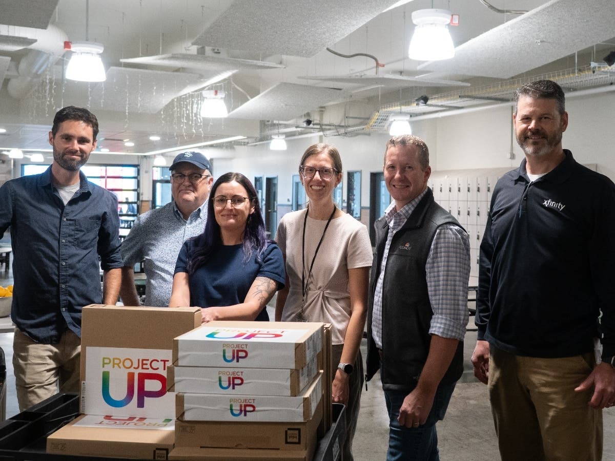 From left to right: Justin Reeves, Alvin Helms, Brittany Hargrove, and Jessica Hess of Lighthouse Mission Ministries receive Comcast-donated laptops from company representatives Vincent Buys and Shawn Robins.