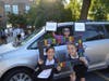 A parent drops off her two smiling middle school students as they begin the school year. 