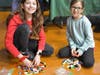 Two smiling students in the beginning stages of building their creations with LEGOs.