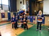 Dina Tsiorvas New York Islanders assembly host and Sparky the Dragon with Willow Road students preparing to work together to dress one student in goalie equipment.