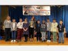 Northern Parkway Elementary School scholars standing on stage after delivering remarks about popular cultural topics and being awarded as champions of the 2nd Annual Uniondale Elementary School Debate Competition.
