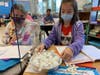 Students constructing a two-story structure using mini marshmallows and toothpicks before placing the structure in a tin filled with ping pong balls or Jell-O, then simulated an earthquake by moving the tin