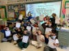 Mrs. Vanessa Broglia’s second graders at Gribbin Elementary School salute the camera while holding their cards.