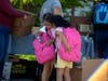 Two students excitedly pick out supplies to put in their matching hot pink backpacks