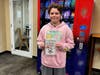 Seventh Grade North Country Road Middle School student Johnny Adler showing off the book he chose from the school’s new book vending machine. 