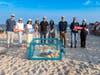 Canon U.S.A. representatives gather on the beach with Amber, the loggerhead sea turtle, prior to her release.